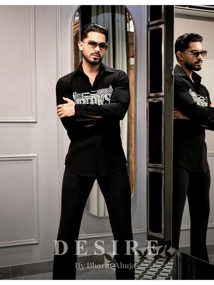 A powerful stance in the 'BAD BOYS' gun shirt. The reflection in the mirror adds depth to this shot of unapologetic confidence.