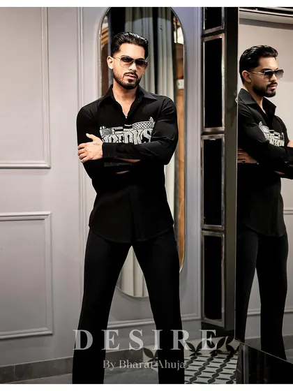 A powerful stance in the 'BAD BOYS' gun shirt. The reflection in the mirror adds depth to this shot of unapologetic confidence.