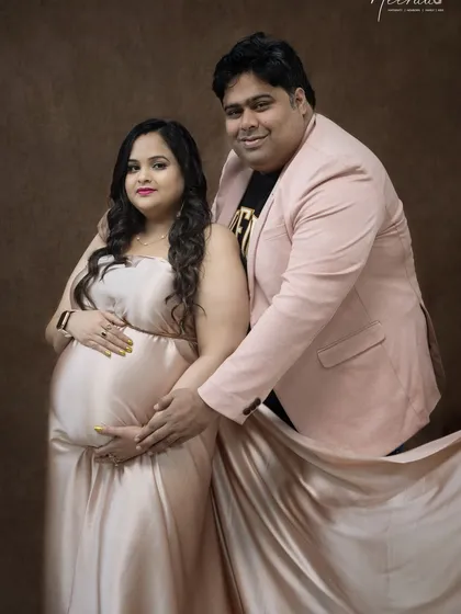 A classic pose that highlights the couple's connection and the beautiful baby bump. The soft, neutral tones of the gown and the studio background create a timeless and elegant look.