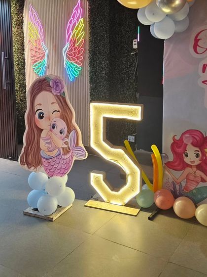 The entrance to the mermaid party featured a cute mermaid cutout and a giant illuminated number '5'. The neon angel wings on the wall added another cool spot for guests to take pictures.