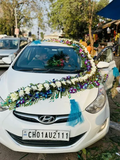 A front view of the wedding car decorated with blue orchids and white flowers. This elegant floral arrangement is perfect for making a statement.