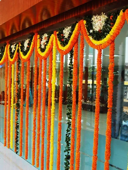 Traditional marigold garlands decorating the glass facade of a building. This is a simple and effective way to bring festive cheer to a home or office exterior.