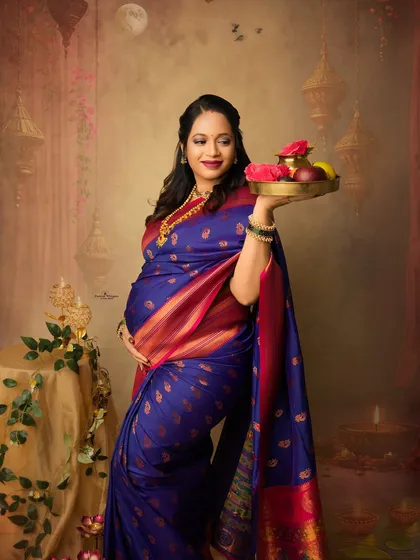 A graceful portrait of the expectant mother holding a tray of offerings. Her pose and the rich colors of her saree create a stunning image that is both traditional and artistic.