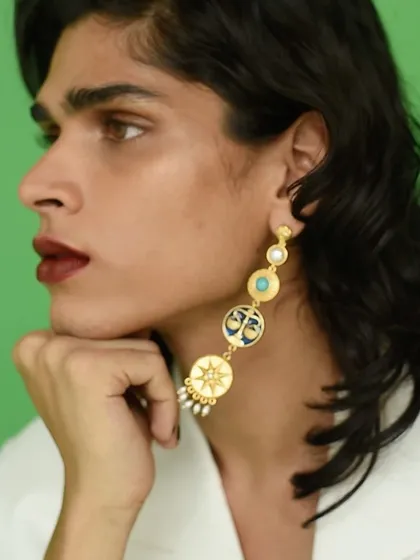 A close-up detail shot for Amama Jewels, focusing on the design of the multi-pendant earring. The composition is clean and product-focused.