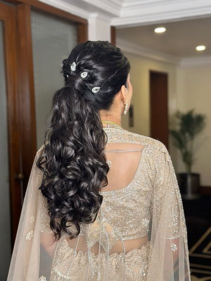 A minimal and gorgeous ponytail. This hairstyle is sleek at the top with beautiful, bouncy curls at the bottom, adorned with simple crystal pins.