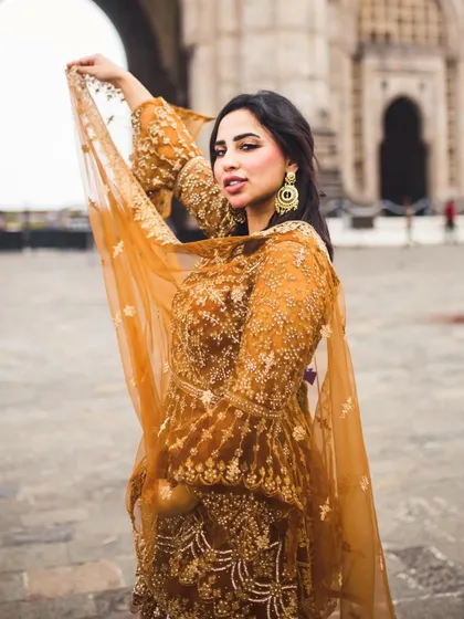 A dynamic bridal portrait where the bride playfully lifts her sheer dupatta. This adds movement and a touch of grace to the photograph.