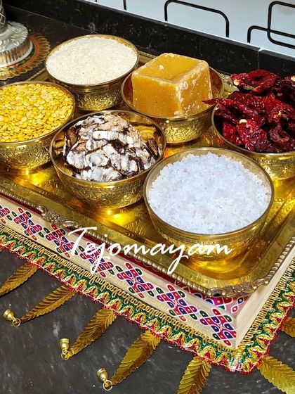 A traditional offering platter for a housewarming pooja, with brass bowls filled with dal, rice, jaggery, and other auspicious items.