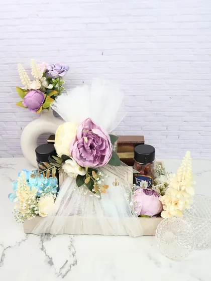 This trousseau packing idea features a beautiful wooden tray adorned with net, flowers, and jars of goodies, perfect for presenting wedding gifts.