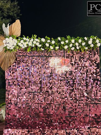 A chic and modern photo booth for a pre-wedding event. This trendy pink sequin wall, topped with white florals and a "Better Together" neon sign, provides a glamorous spot for guests to take pictures.