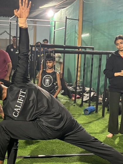 A coach demonstrates the extended side angle pose (Utthita Parsvakonasana), a yoga asana that stretches the entire side of the body from the heel to the fingertips.