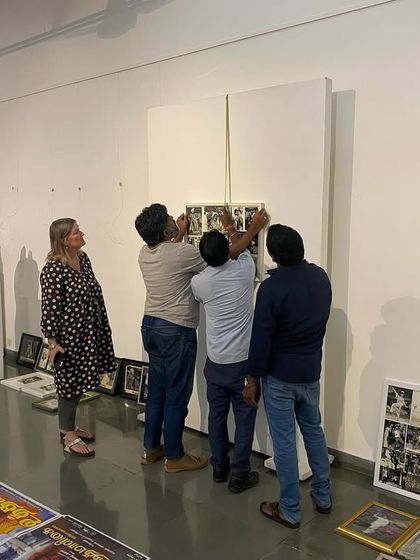 The team carefully hanging a grid of small photographs for 'Southern Stars'.