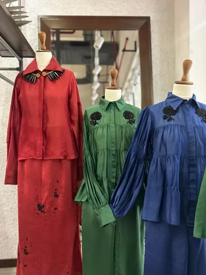 A vibrant display of red, green, and blue co-ord sets, each with unique black embellishments, from paint splatters to floral motifs.