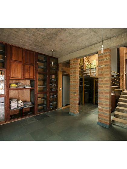 The library in the Professor's Residence, featuring bookshelves made from Cuddapah stone. The space is designed with a mix of earth blocks and stone flooring, demonstrating our use of diverse natural materials.