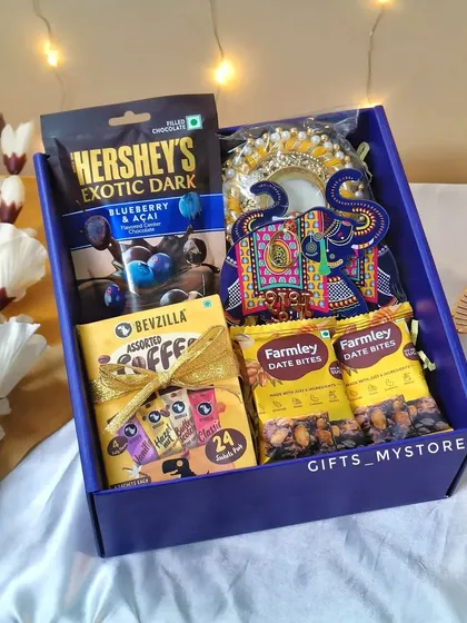 A look inside our blue corporate gift box. It's filled with Hershey's Exotic Dark chocolates, Bevzilla assorted coffee, Farmley date bites, and a traditional decorative elephant 'shubh labh' for good luck.