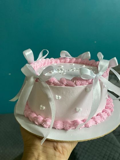 A side view of the farewell cake, showcasing the delicate bows and heart sprinkles.