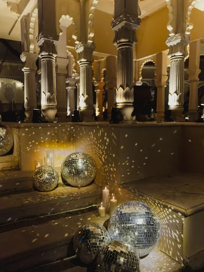 Disco balls and candles illuminate the steps of a heritage venue, blending modern party vibes with timeless architecture for a unique after-party setting.