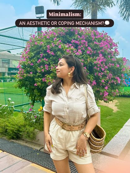 A side profile of the minimalist beige romper look. The gold earrings and wide belt add a touch of sophistication to the simple outfit.