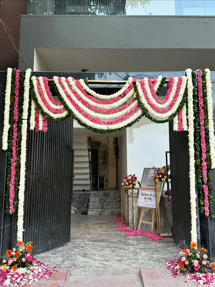 A traditional and beautiful floral entrance for a Griha Pravesh (housewarming) ceremony. We used garlands of pink and white flowers to create a welcoming arch over the main gate.