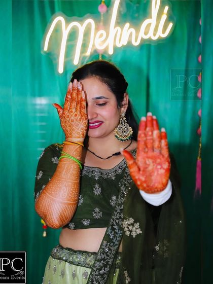 A playful shot of the bride. The 'Mehndi' neon sign in the background adds a fun, modern element to her traditional photos.