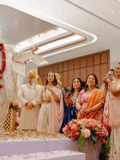 The couple on stage during the Varmala ceremony, surrounded by their happy families. We design our stages to ensure everyone has a great view of these key moments.