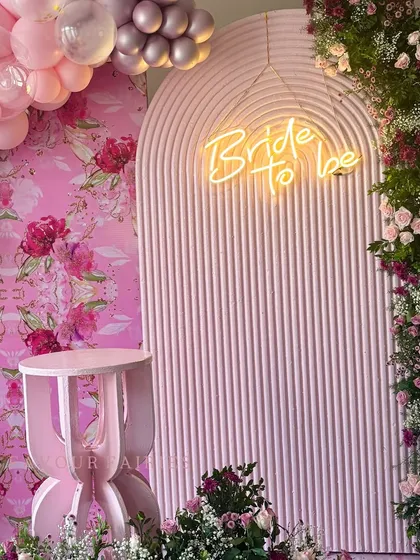 A close-up of this pink 'Bride to be' setup, highlighting the neon sign against a textured arch. The combination of balloons, a custom floral wallpaper, and fresh flowers created a rich, layered look.