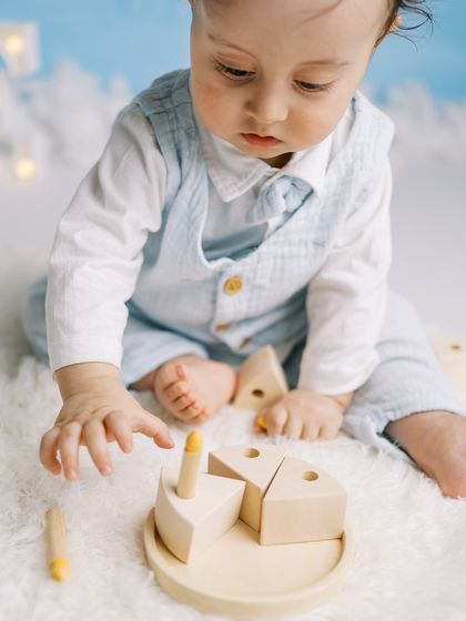 A close-up of the birthday boy playing with his wooden cake set against the hand-painted sky backdrop.