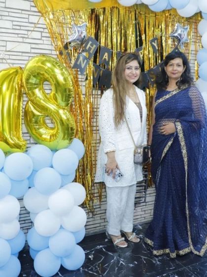 A photo of our lead nutritionist and a guest in front of the celebration backdrop for our 18th anniversary.