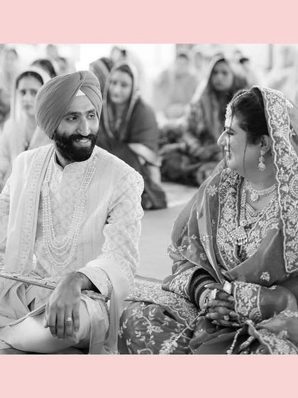 A quiet, shared glance between the bride and groom during their Anand Karaj ceremony. This black and white shot, framed by a soft pink border, highlights their connection amidst the sacred rituals.