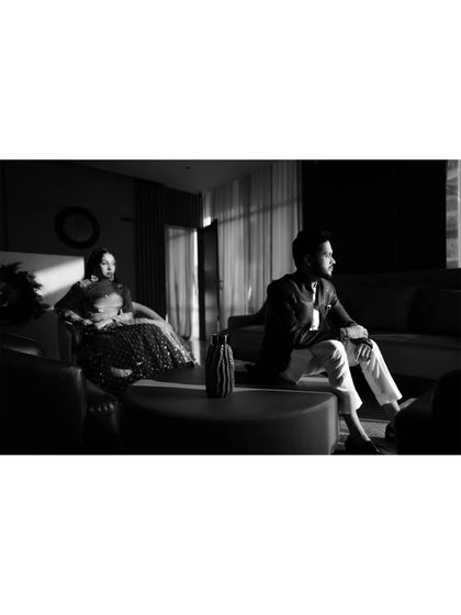 A moody black and white shot of the couple seated in a modern, stylish lounge, creating a cinematic feel.