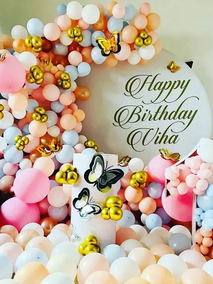 A beautiful close-up of a butterfly-themed cake table area, with a cascade of pastel balloons and elegant butterfly cutouts.