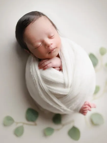 A touch of green. This minimal setup with a simple white wrap and a few eucalyptus leaves creates a fresh, natural, and modern portrait.