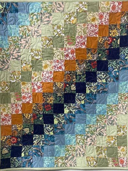 A colorful patchwork quilt with a gradient effect, moving from light to dark blues and greens.
