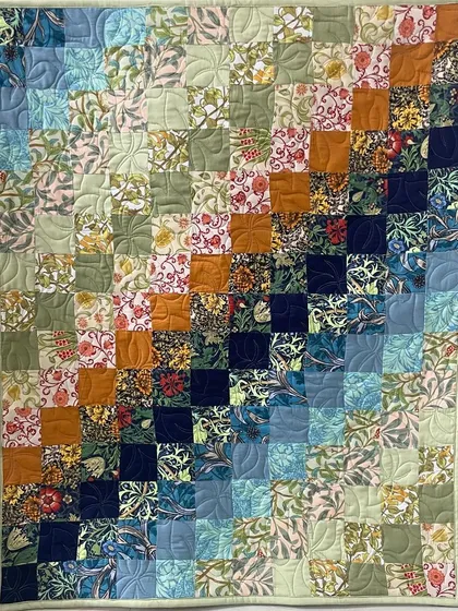 A colorful patchwork quilt with a gradient effect, moving from light to dark blues and greens.