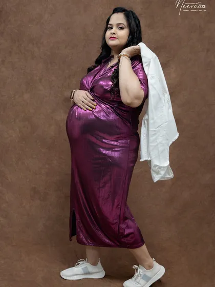 A cool and modern maternity portrait. The metallic dress paired with sneakers and a jacket over the shoulder shows a fun, contemporary style.