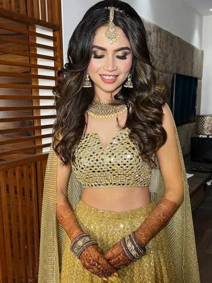 The complete Sangeet look. The golden lehenga, soft curls, and sparkling makeup are perfect for a night of dancing.