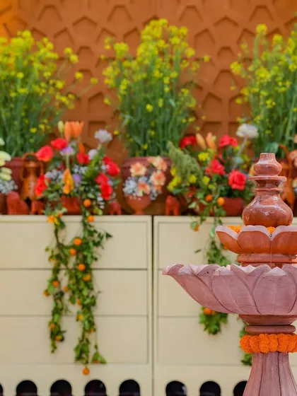 A beautiful setup featuring a stone fountain and a floral display against a carved backdrop. The cascading citrus vines add a fresh, organic touch to the arrangement.