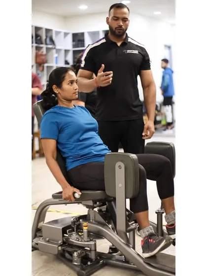 A trainer explains the mechanics of the hip adduction machine to a member, providing the knowledge she needs for an effective workout.