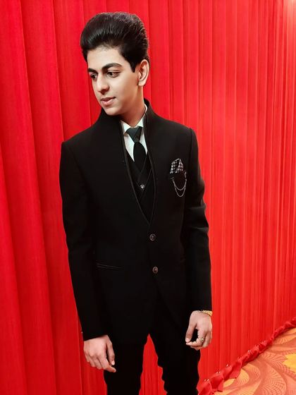 A candid shot of the same client against a red backdrop. The professional grooming ensures he looks great from every angle, whether posed or in motion.