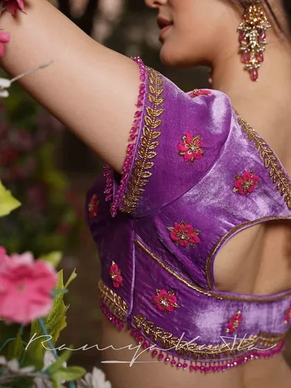 The back of the lavender velvet blouse reveals a stylish cutout, edged with intricate zardosi and beadwork. A delicate beaded tassel adds a final touch of grace to this sangeet-ready piece.