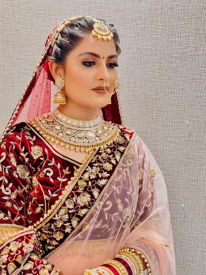 A picture of bridal perfection. This look features intricate hair styling with a traditional maang tikka and flawless HD makeup, highlighting the bride's natural beauty for her special day.
