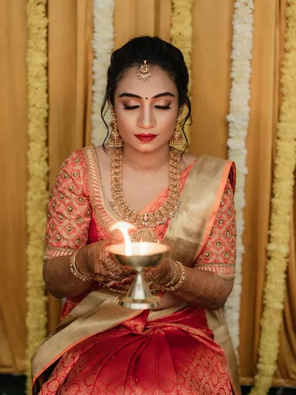 This is the look I absolutely love creating. For her bangle ceremony, we went with a classic South Indian style, focusing on flawless skin, bold red lips, and eyes that tell a story. It's all about capturing that serene, traditional glow.