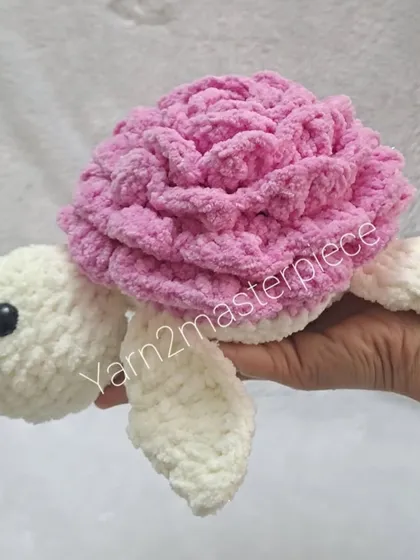 A side view of the cream and pink rose turtle, highlighting its plush texture and friendly eyes.