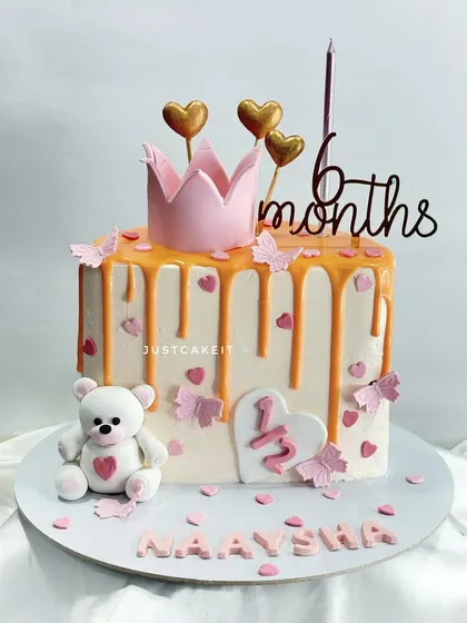 A half-birthday cake to celebrate a baby turning 6 months old. The design features a cute teddy bear, a crown, and a pretty pink drip.