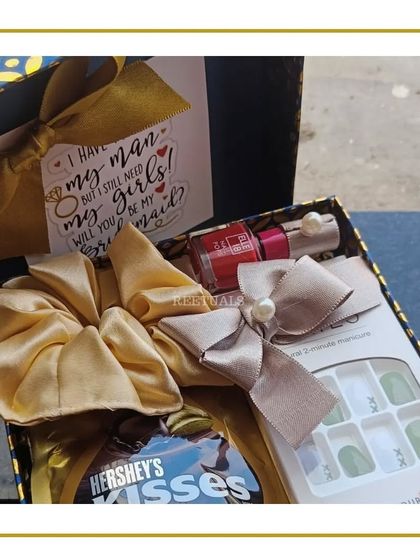 A close-up of the contents of a bridesmaid box, featuring a satin scrunchie, nail polish, and a personalized card, showing the attention to detail in each gift.