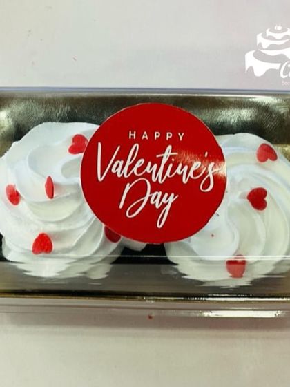 Two simple yet elegant cupcakes for Valentine's Day. They are topped with white frosting and red heart sprinkles, and come packed in a clear gift box.