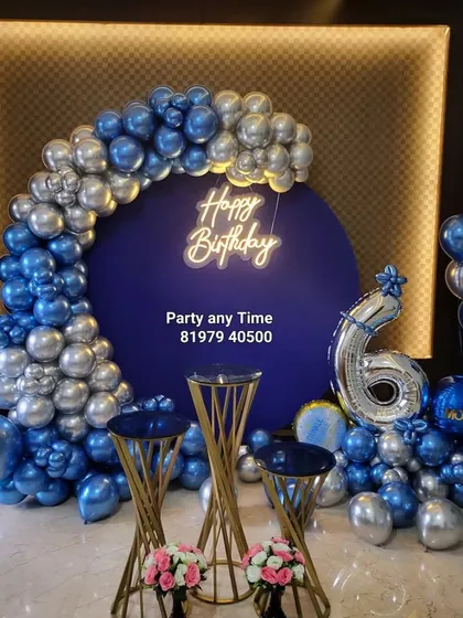 A stunning blue and silver chrome balloon arch against a dark blue backdrop for a 6-month birthday celebration.