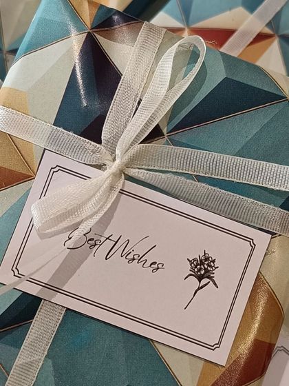 A beautifully wrapped gift with a simple 'Best Wishes' card and a delicate ribbon.