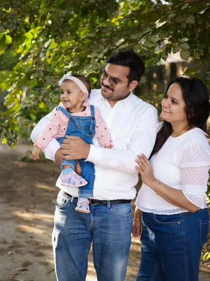 A happy family enjoying a walk in the park. The sunlight filtering through the trees creates a warm and beautiful glow.