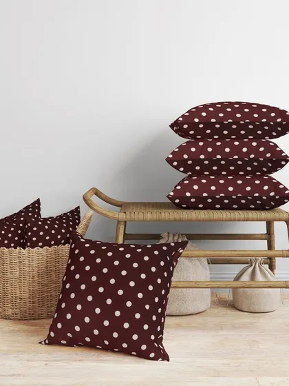 A collection of maroon polka dot cushions styled in a rustic home setting. This helps customers imagine the product in their home and see how multiple items look together.