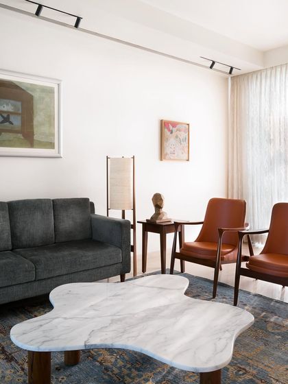 This living room features a mix of seating I curated and designed, including a grey sofa and leather armchairs. The custom, free-form marble coffee table acts as a sculptural centerpiece, grounding the space.